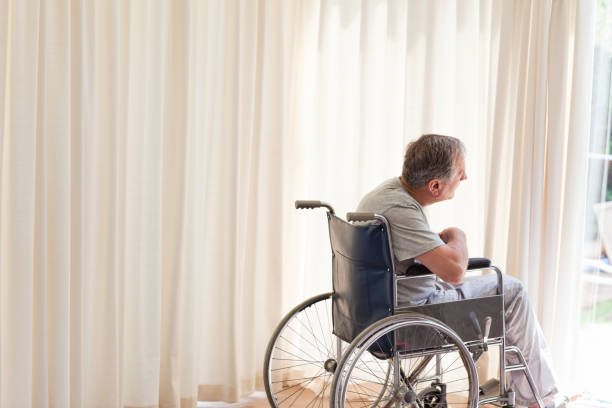 istock Man in his wheelchair looking out the window 826130346