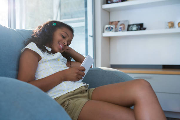 istock Smiling girl using tablet while sitting on armchair 826131758