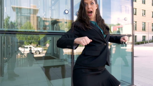 A businesswoman crazy dancing celebrating her success outside office building