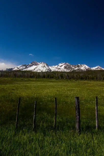 A cool perspective of barbed-wire fenceposts in front of the Sawtooth Mountains.