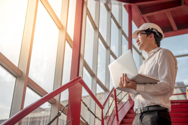 young asian engenheiro ou arquiteto que trabalha com o laptop - architect construction engineer standing - fotografias e filmes do acervo