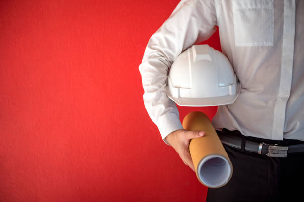 istock Engineer or Architect holding safety helmet and architectural drawing in red background 826144024