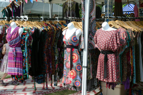 Fashionable clothing on mannequins outside store, long dresses and skirts in natural colors, displayed next to townhouse