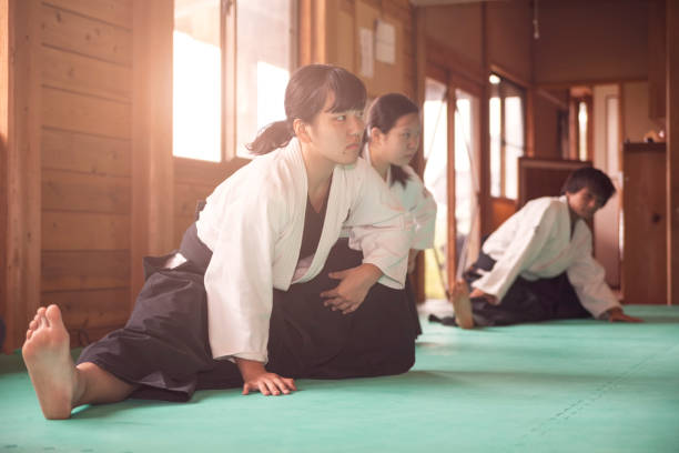 Warming Up Before Practice Three martial art practitioners are warming up before practicing. japan women human foot japanese culture stock pictures, royalty-free photos & images