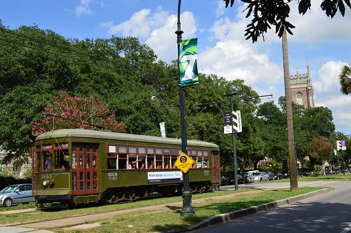 New Orleans, Louisiana - July 17, 2015:  historic street cars on the St. Charles Avenue line are powered by electricity, and they have been in service since the early 1900's.  The street cars are original, and they still do not have air conditioning, but they do have plenty of windows to open on warm days.  They are part of the New Orleans Transit Authority, which provides mass transportation to the area.