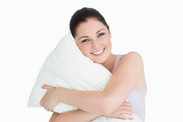 istock Smiling woman holding a pillow against white background 826166746
