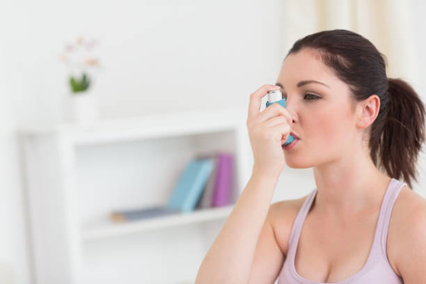 istock Woman using asthma inhaler in living room 826166982