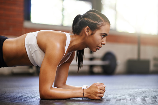 Shot of an attractive young woman doing push ups in a gym