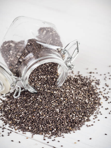 chia seeds scattered from glass jar on white background chia seeds scattered from glass jar on white background. Copy space. eating chia seeds stock pictures, royalty-free photos & images