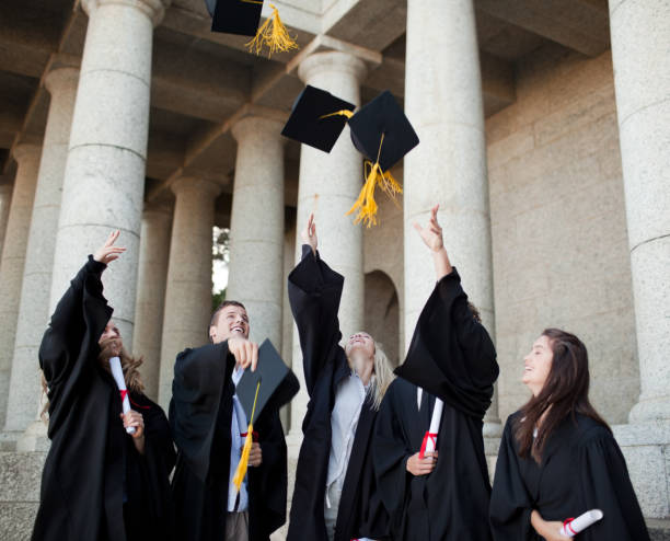 istock Smiling graduates throwing their hats in the sky 826171190