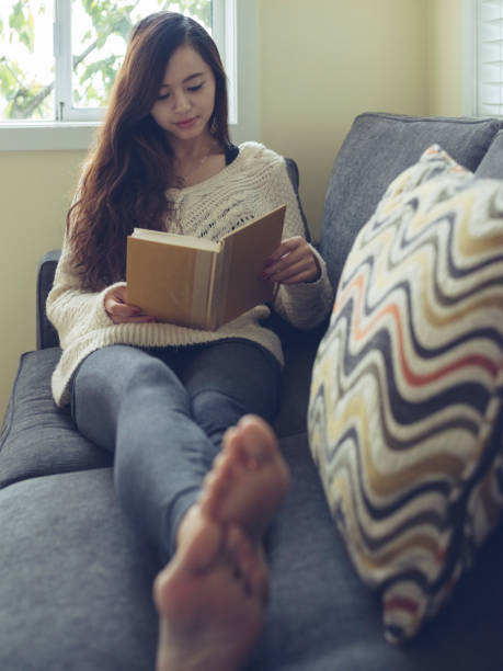 istock woman reading a book on sofa 826172098