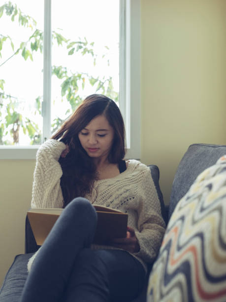istock woman reading a book on sofa 826174370