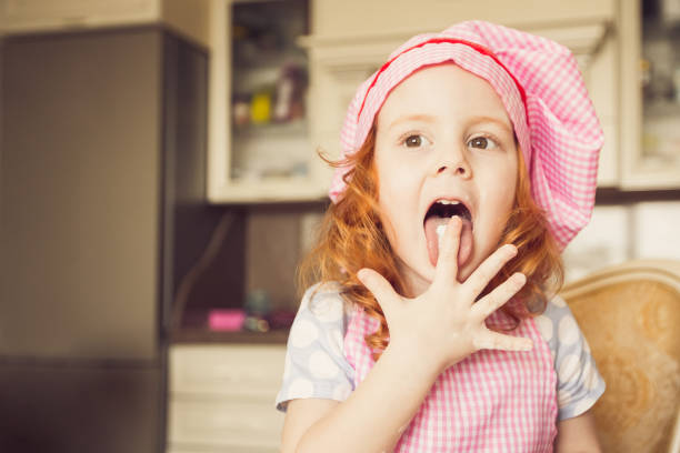 zabawna dziewczynka w kucharzach kapelusz lizanie palce - hat toddler little girls pink zdjęcia i obrazy z banku zdjęć