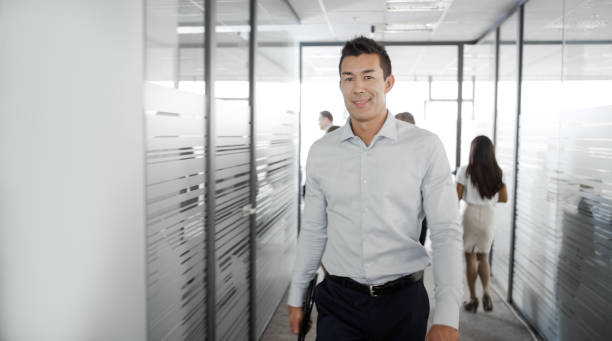 istock Businessman smiling as he walks down office hallway 826183600