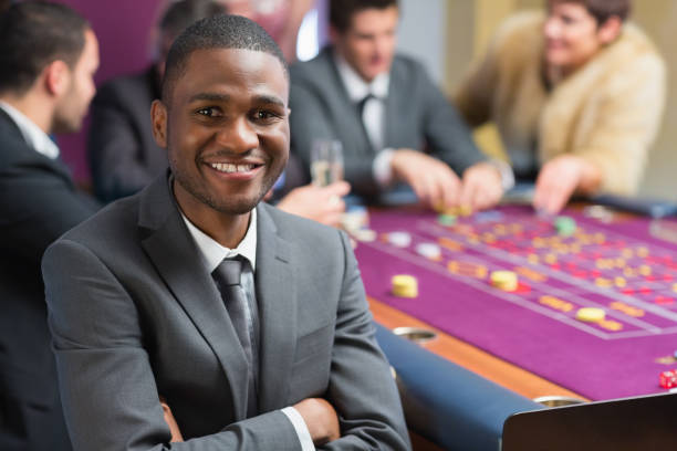 homme souriant, assis les bras croisés à roulette - casino black and white gambling chip gambling photos et images de collection