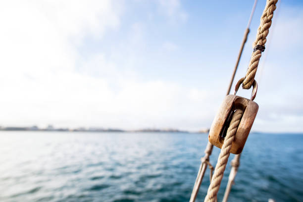 wooden pulley with a rope on a rigging vintage sailing boat wooden pulley with a rope on a rigging vintage sailing boat with saint-malo city at the blur background during a sunny sea trip in brittany ille et vilaine stock pictures, royalty-free photos & images