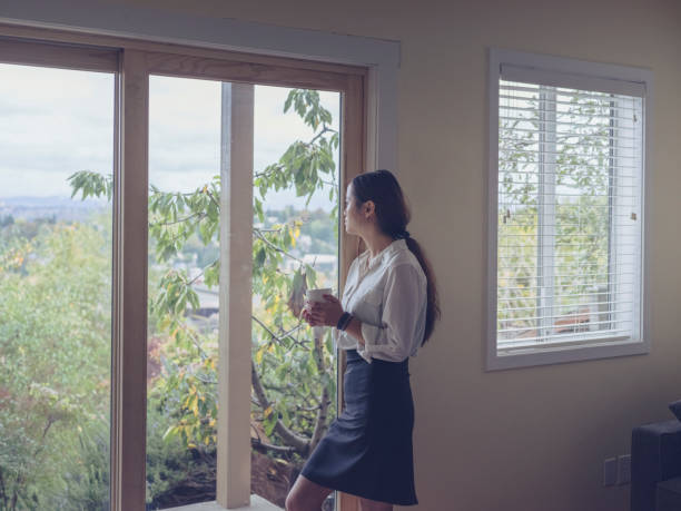 istock woman drinking water at window and looking out 826200614