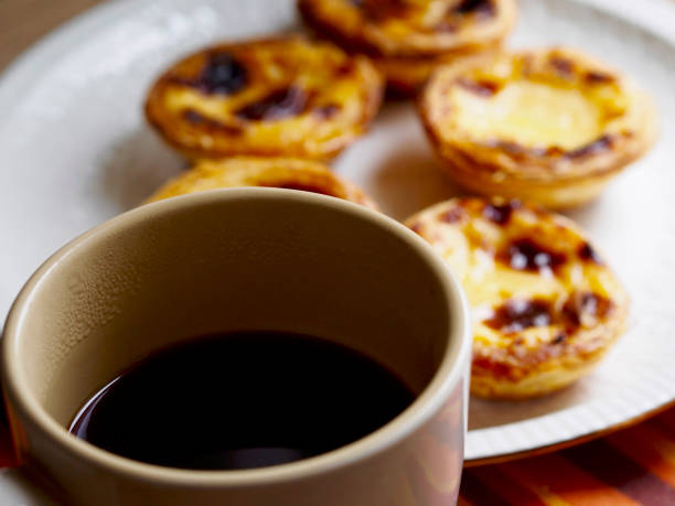 istock Softfocus custard tarts in a plate  and black coffee cup 826211016