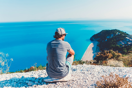 Young male enjoying the view from a view point, Greek paradise beach, Greek islands, Mediterranean sea, morning light, world is a beautiful place