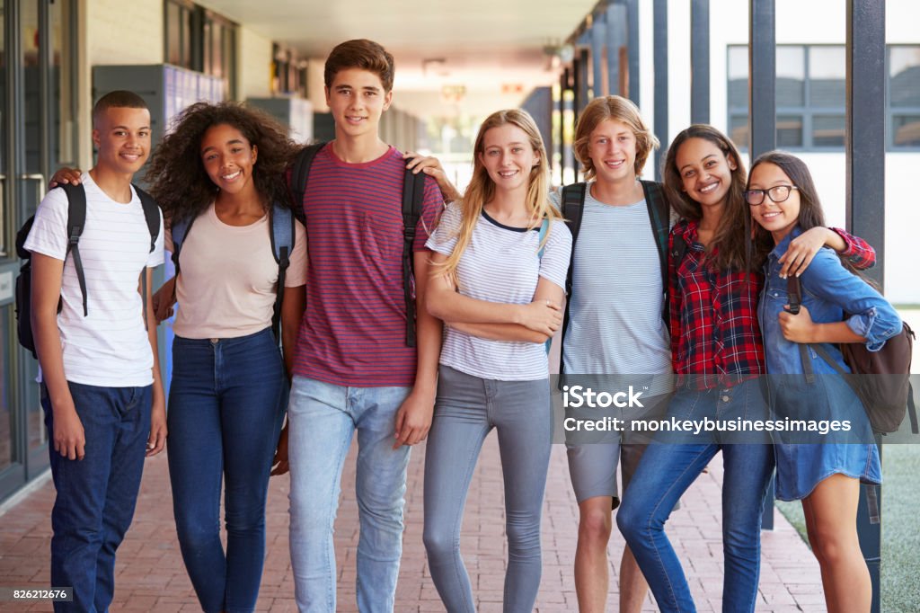Compagni di classe adolescenti in piedi nel corridoio del liceo - Foto stock royalty-free di Adolescente