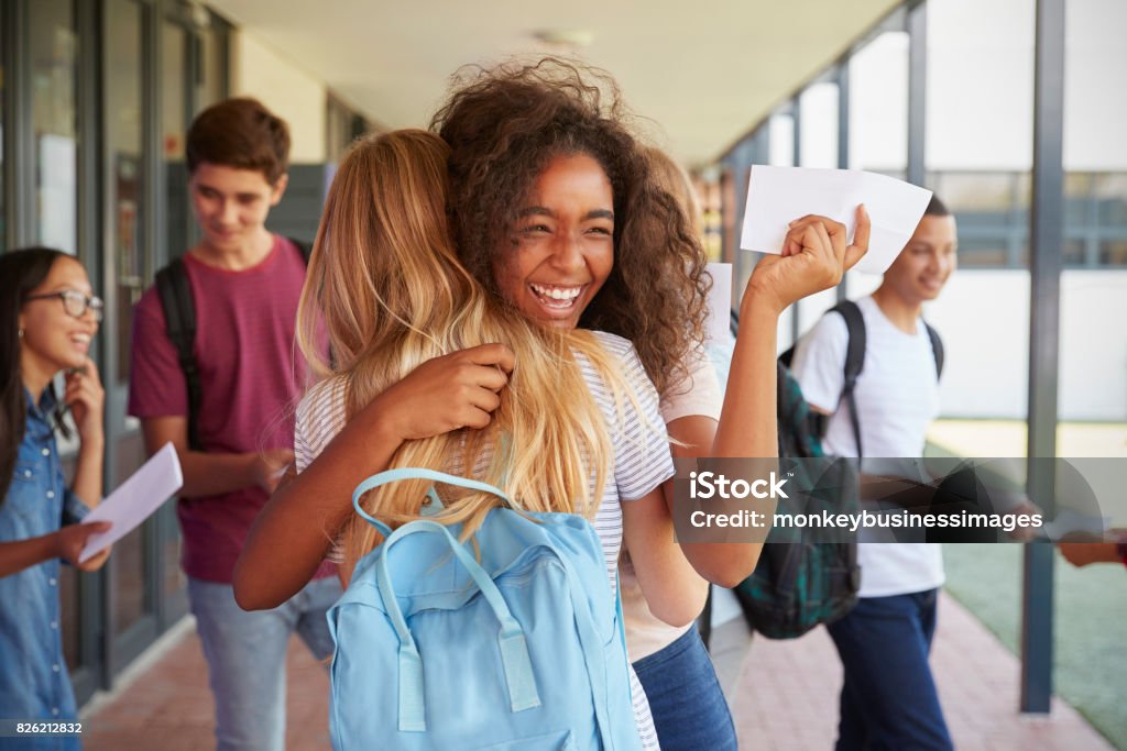 Dos chicas celebrando los resultados de los exámenes en corredor de escuela - Foto de stock de Adolescente libre de derechos