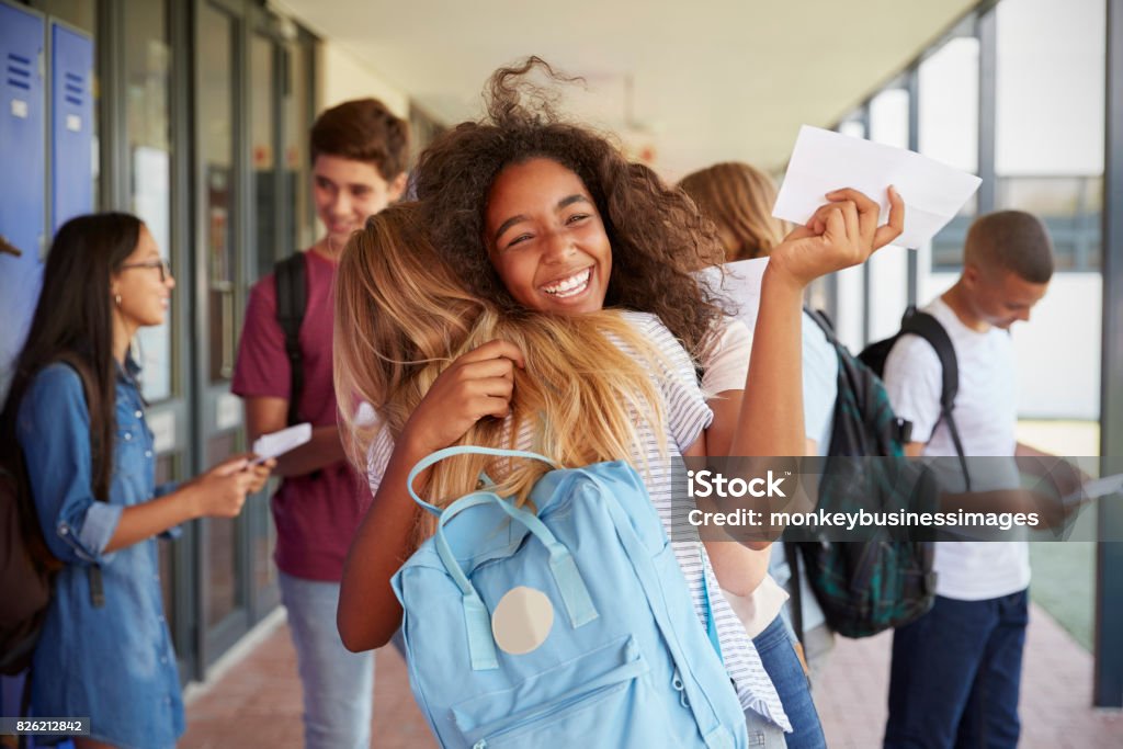 Two girls celebrating exam results in school corridor Education Stock Photo