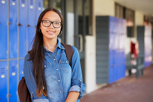 Happy Asian teenage girl smiling in high school corridor