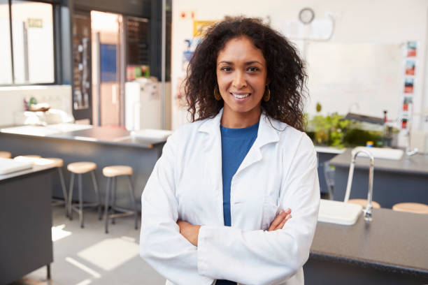 istock Female teacher in lab coat smiling in school science room 826213532