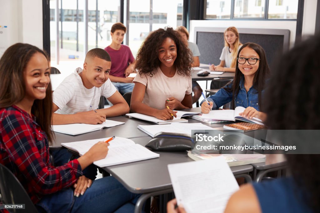 High school kids looking to teacher sitting at their desk Teenager Stock Photo