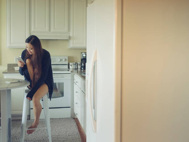 istock woman texting her phone in kitchen 826217394