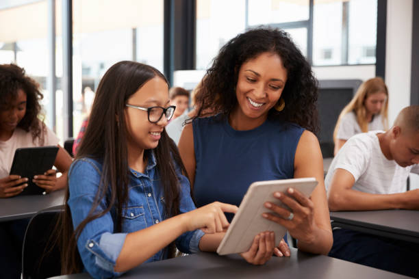 teacher helping teenage schoolgirl with tablet computer - multi ethnic group concentration student asian ethnicity imagens e fotografias de stock