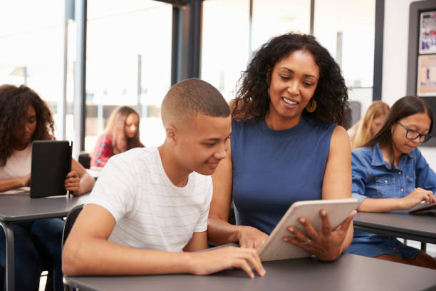 istock Teacher helping teenage schoolboy with tablet computer 826220604