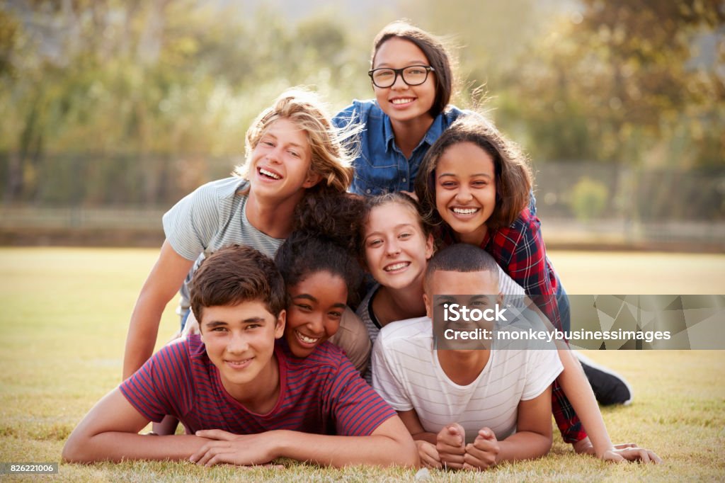 Group of teenage friends lying in a pile on grass Teenager Stock Photo