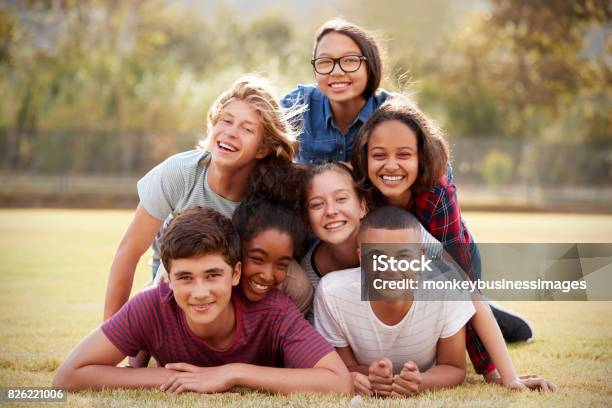 Group Of Teenage Friends Lying In A Pile On Grass Stock Photo - Download Image Now - Teenager, Adolescence, Multiracial Group