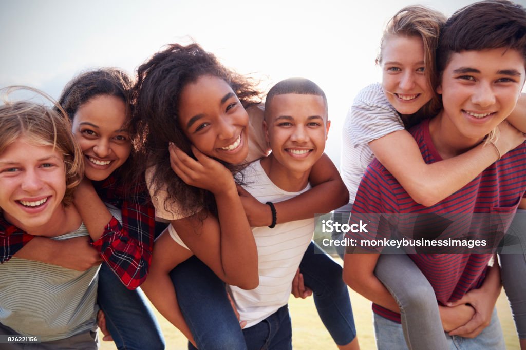 Amigos adolescentes que se divierten al aire libre piggybacking - Foto de stock de Adolescente libre de derechos