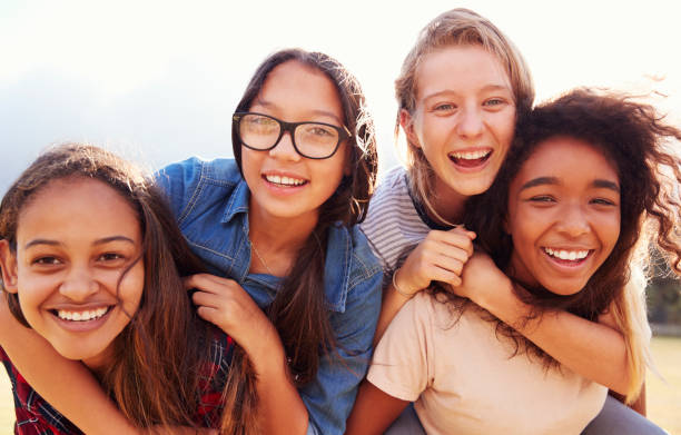 cuatro adolescentes que se divierten al aire libre piggybacking - sólo niñas fotografías e imágenes de stock