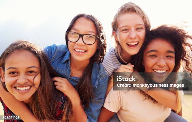 Cuatro Adolescentes Que Se Divierten Al Aire Libre Piggybacking Foto de stock y más banco de imágenes de Niñas