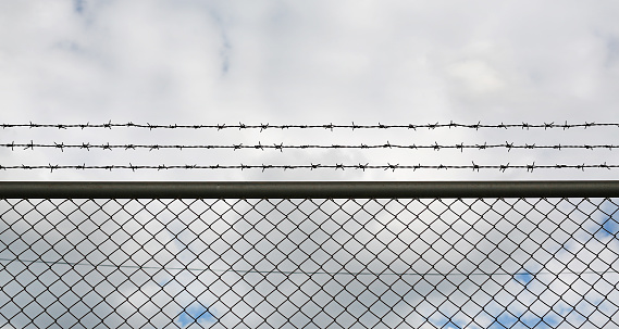 Barbed wire fence with dark clouds.