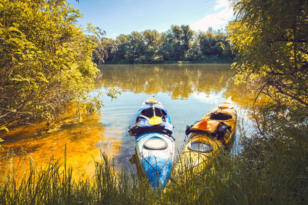 Camping kayaks on the river bank on a sunny day.