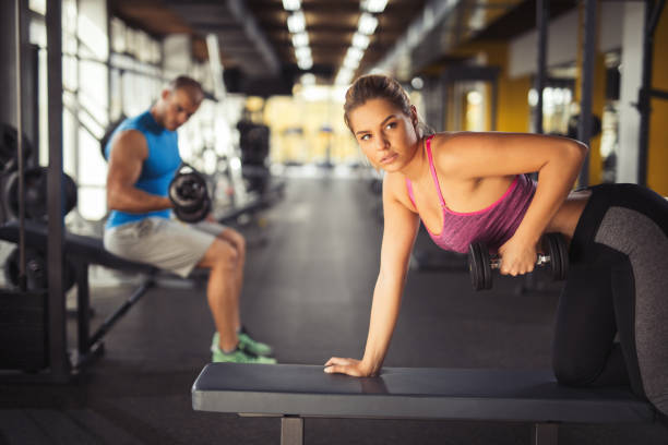 istock Young woman having weight training with dumbbells at gym 826236380