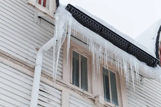 Photo of Large icicles hang on the facade of wooden house