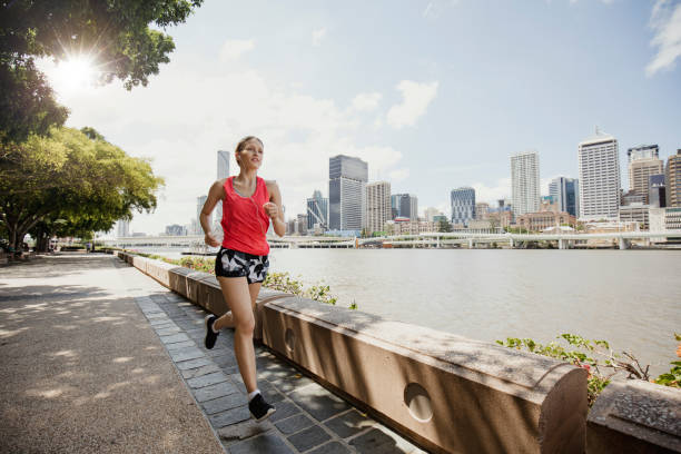 Young Woman Jogging on Brisbane Southbank Young woman dressed in sports clothing going for a jog along Brisbane Southbank. sports training australia stock pictures, royalty-free photos & images