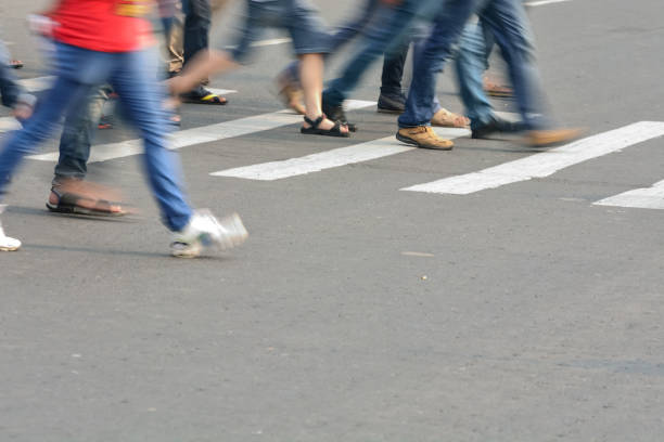Motion blurred, pedestrians crossing street on zebra crossing.
