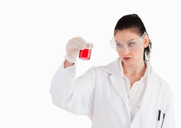 istock Darkhaired scientist with safety glasses looking at a red beaker 826255358