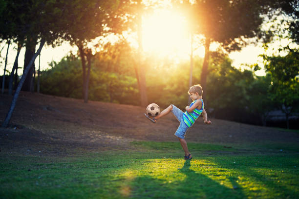 маленький мальчик практикующий футбол держать окна в парке - soccer child little boys playing стоковые фото и изображения