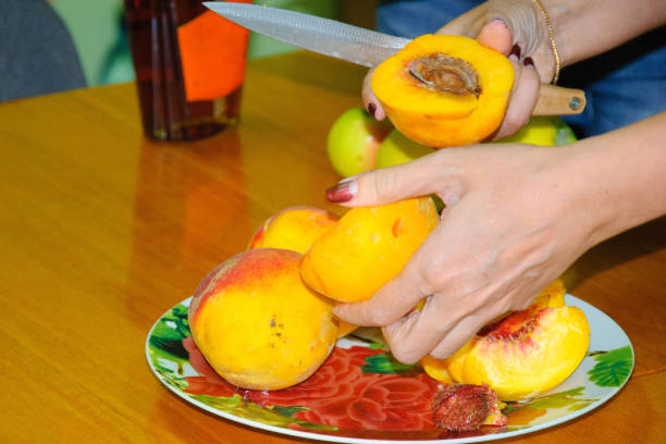 istock Hands are cutting peaches over a plate 826275516
