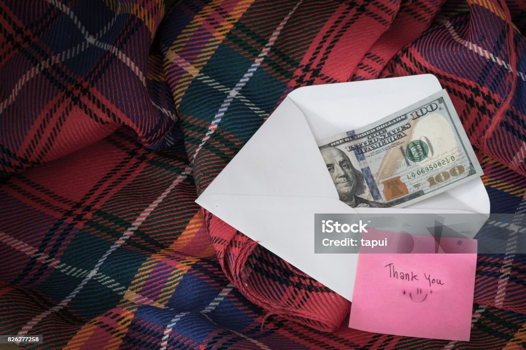 Money in a white envelope, put on a blanket, along with a thank you message. Currency Stock Photo