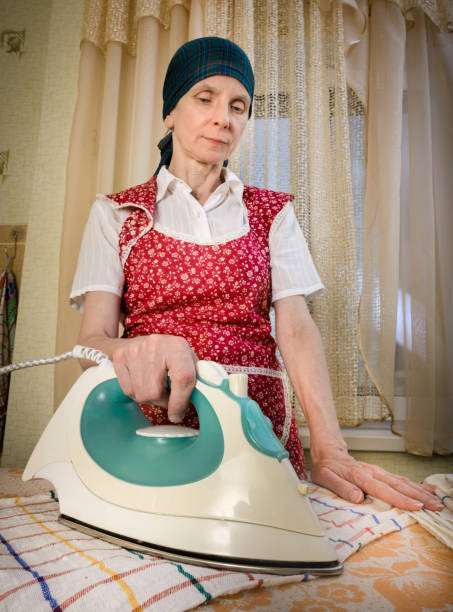 woman ironing in the kitchen - appliance living room domestic room lifestyles imagens e fotografias de stock