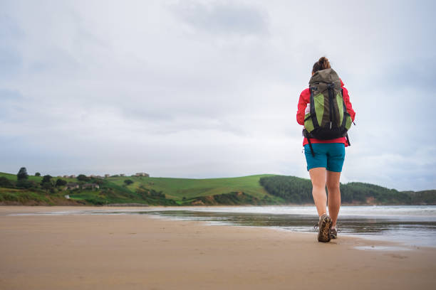 istock Backpacker girl traveler walk on deserted ocen beach 826283750