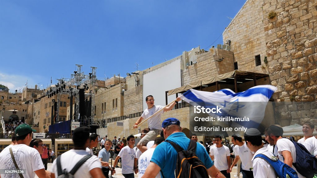 Jews dancing in a round with flag in Jerusalem Jerusalem, Israel - May 25, 2017: Jews dancing in a round with flag celebrating the Jerusalem Day at Western Wall - Wailing Wall or Kotel - the most sacred place for all jews and jewish in the world. All West Asian Flags Stock Photo